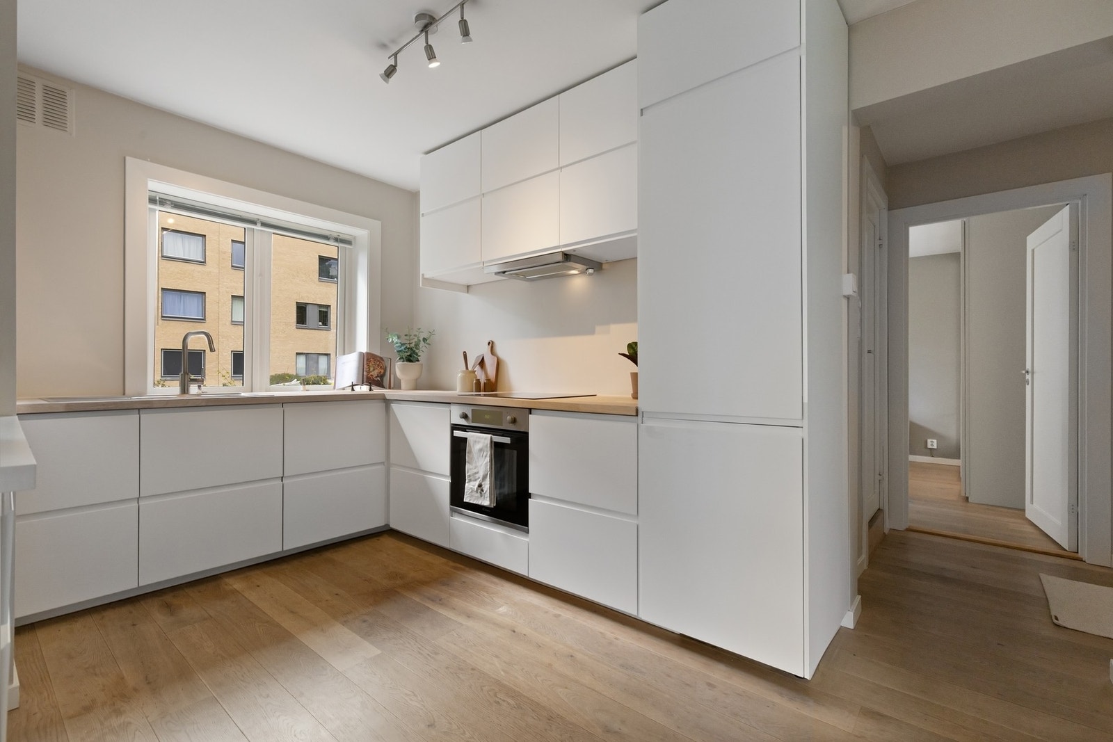 Stilrent og moderne kjøkken med glatte, hvite fronter og helhetlige løsninger som gir et ryddig og moderne preg. Galleribilde