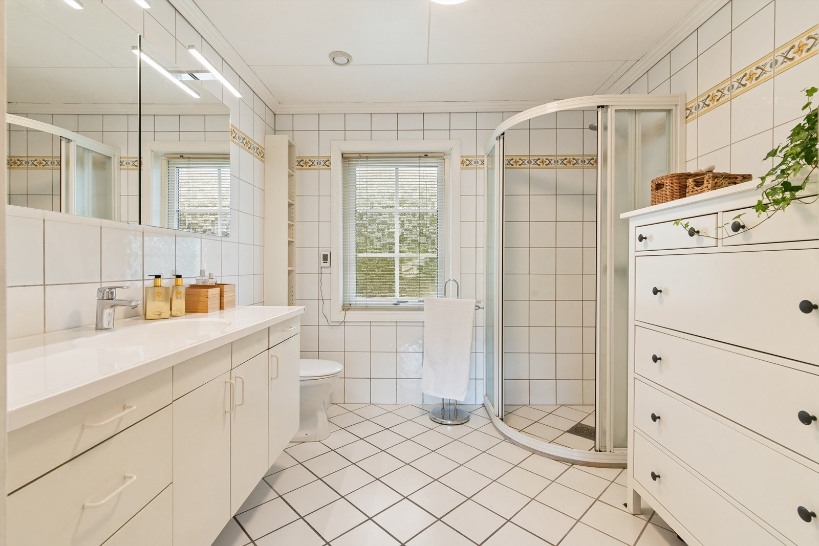Badet er utstyrt med toalett, servant, dusj, innredning med glatte fronter og speilskap, samt elektriske varmekabler i gulvet. Galleribilde