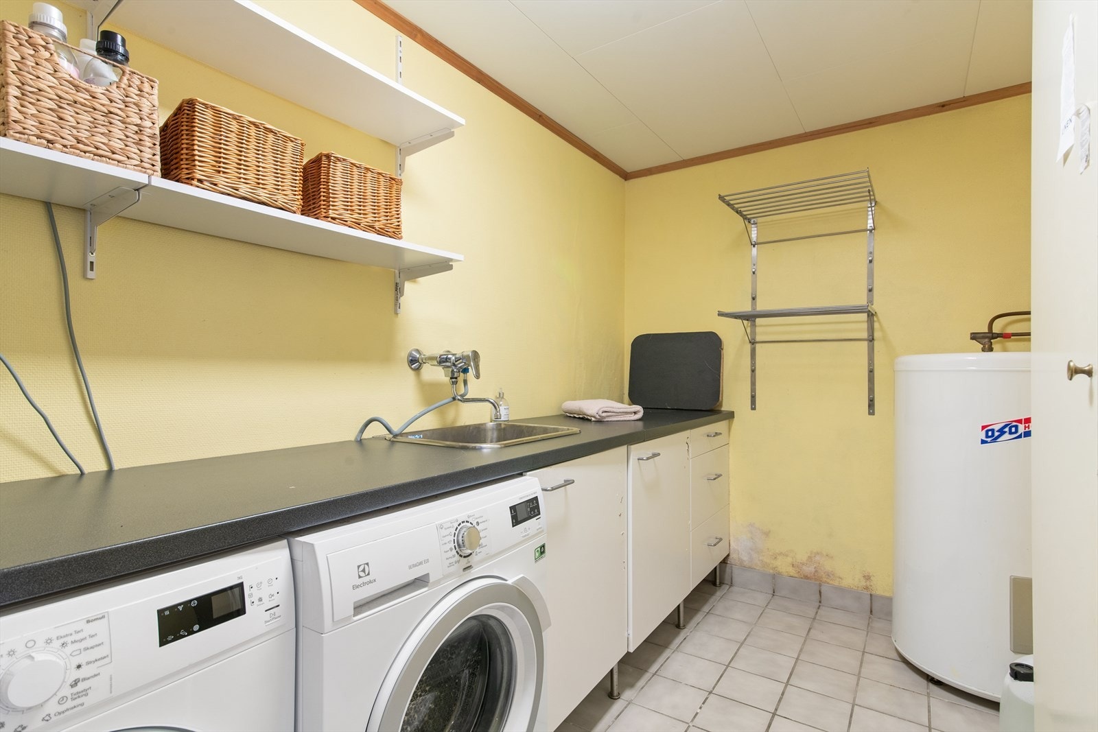 Praktisk og romslig vaskerom utstyrt med skyllekum samt opplegg for vaskemaskin og tørketrommel. Galleribilde