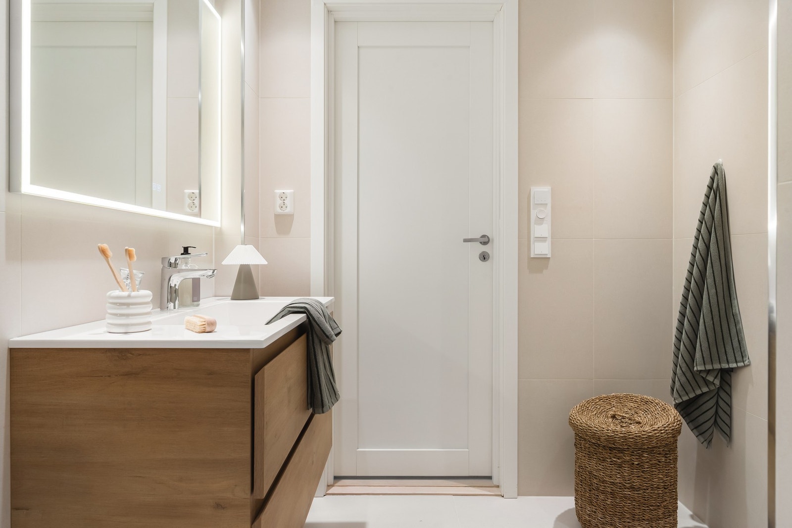 Badet er helfliset og holder en gjennomført stil med innfelte downlights, varmekabler i gulv, vegghengt toalett, dusj med glassvegg, baderomsinnredning samt opplegg for vaskemaskin. Galleribilde