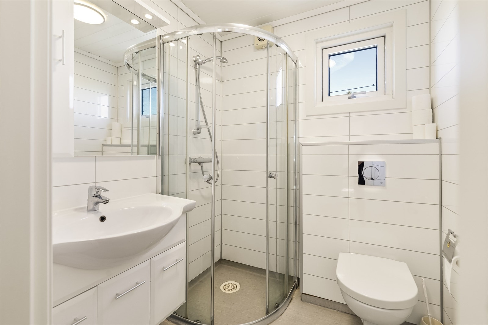 Badet er innredet med dusjnisje, vegghengt toalett og servant med underskap. Galleribilde