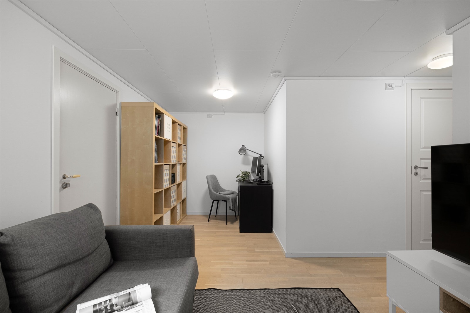 Kjellerstue med plass til både sofa, tv og en kontorplass. Galleribilde