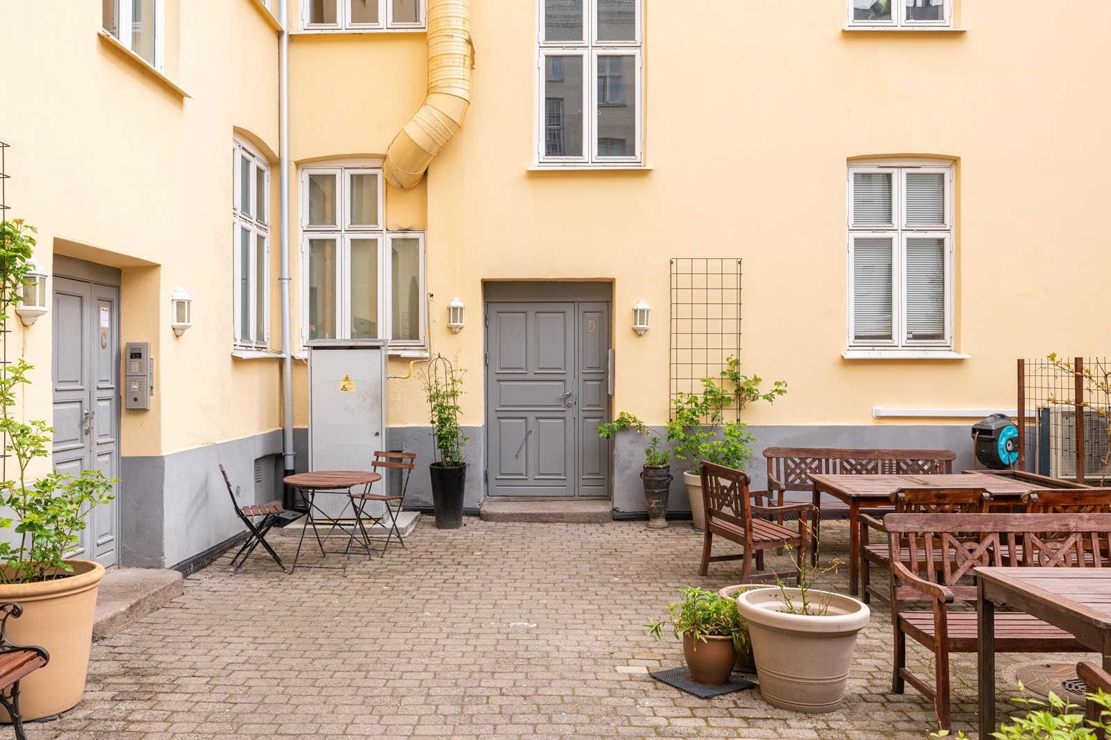 Felles bakgård med sitteplasser og brostein, skjermet fra bylivet utenfor Galleribilde