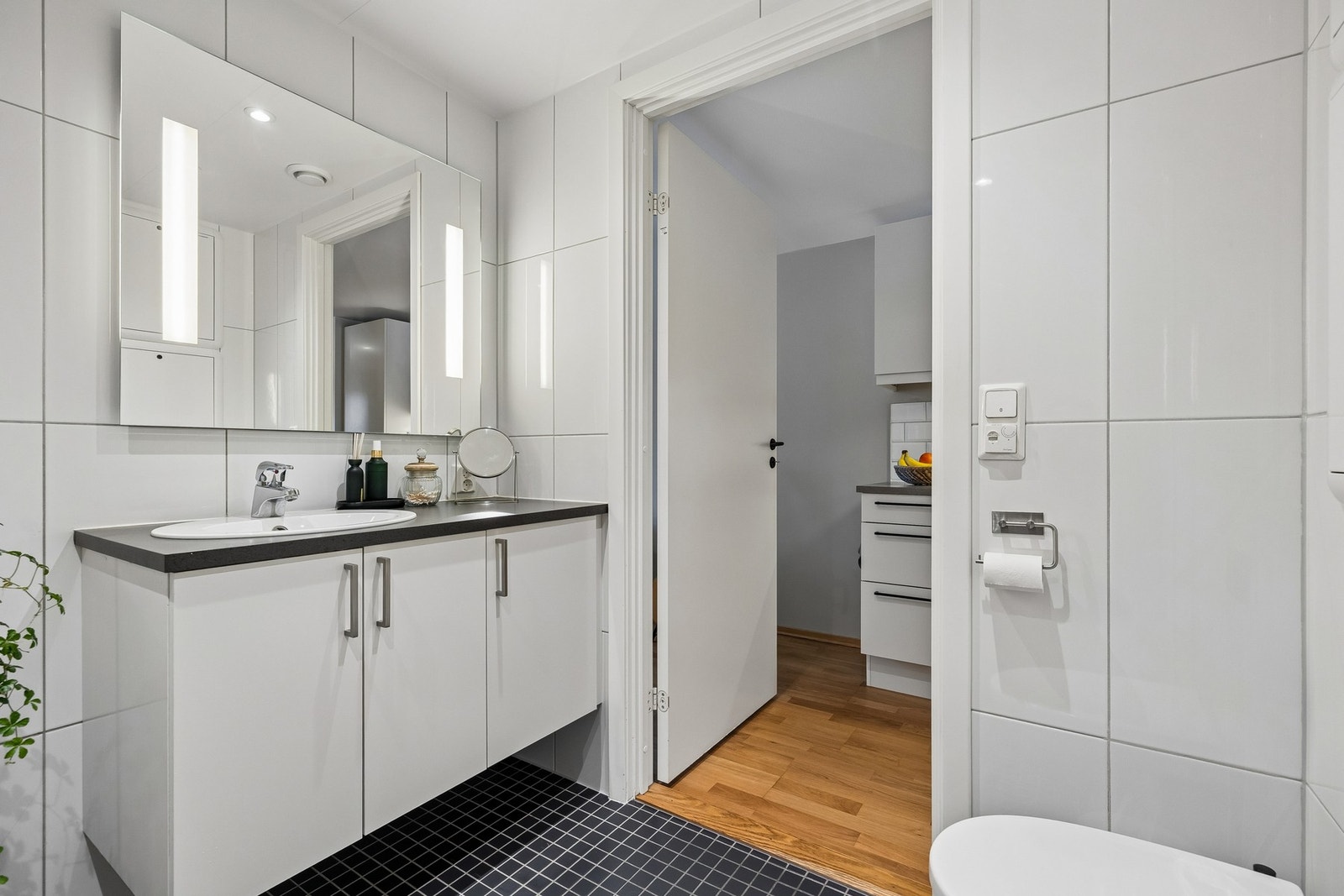 Videre er badet innredet med servantskap med speil og lys, vegghengt toalett og dusjhjørne. Galleribilde