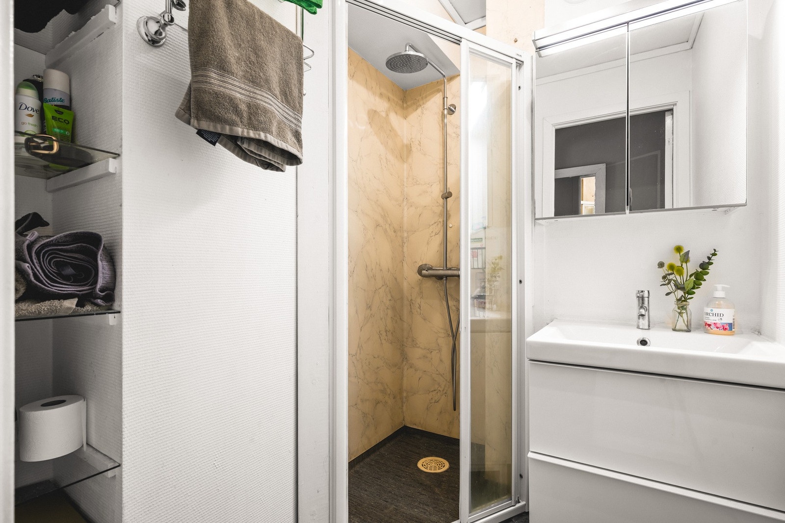 Badet måler 2,1 m² og har helstøpt servant, skuffer under servant med slette fronter, og dusjdører i klart glass. Galleribilde