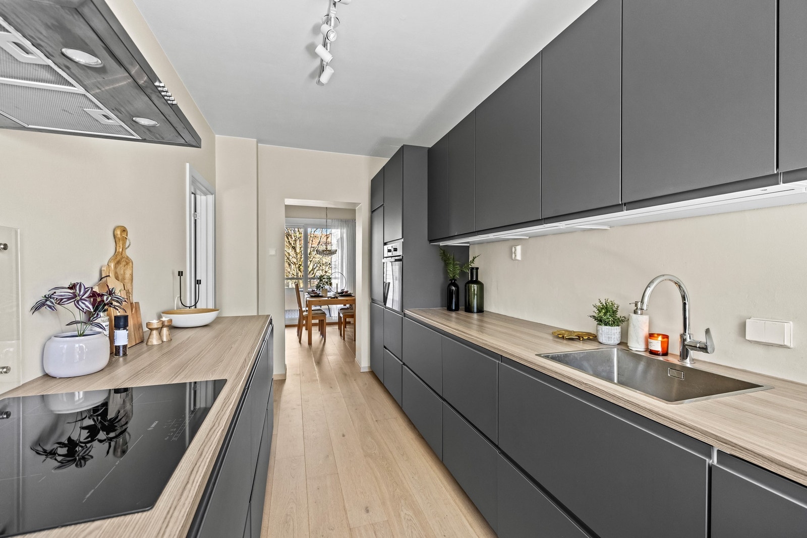 Glatte, mørke fronter gir et moderne uttrykk, komplementert av en lys benkeplate i laminat. Galleribilde