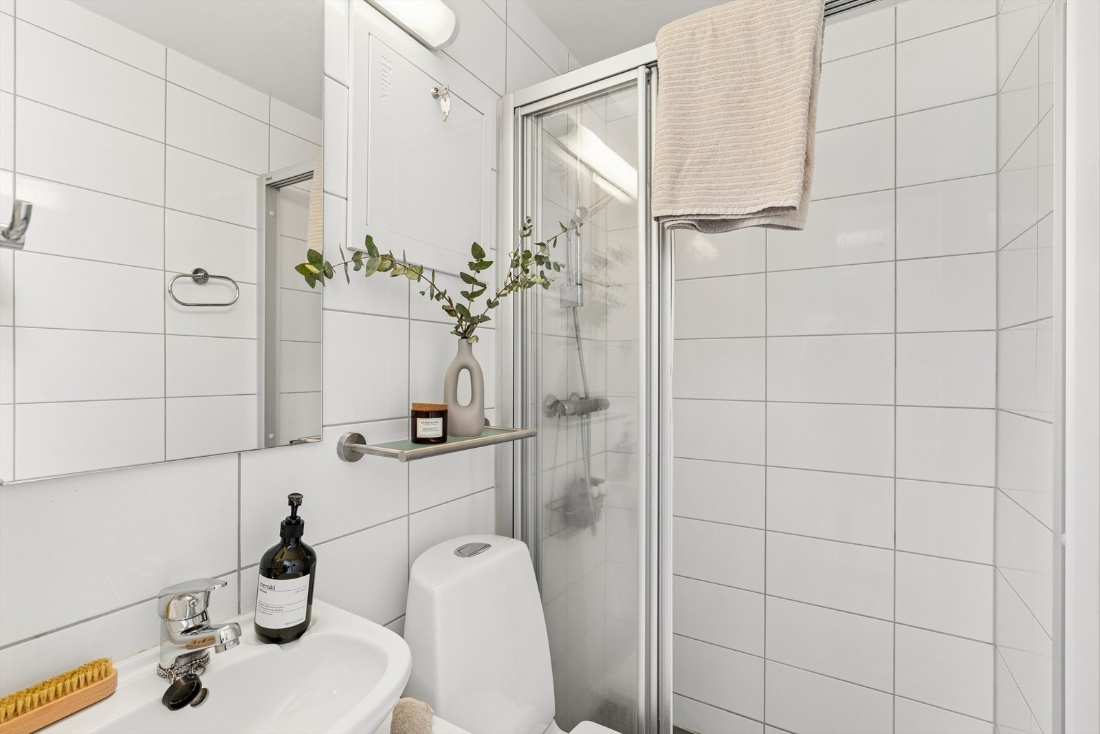 Badet består av frittstående wc, servant m/underskap, speil m/overlys og lukket dusjhjørne m/skyvedører Galleribilde