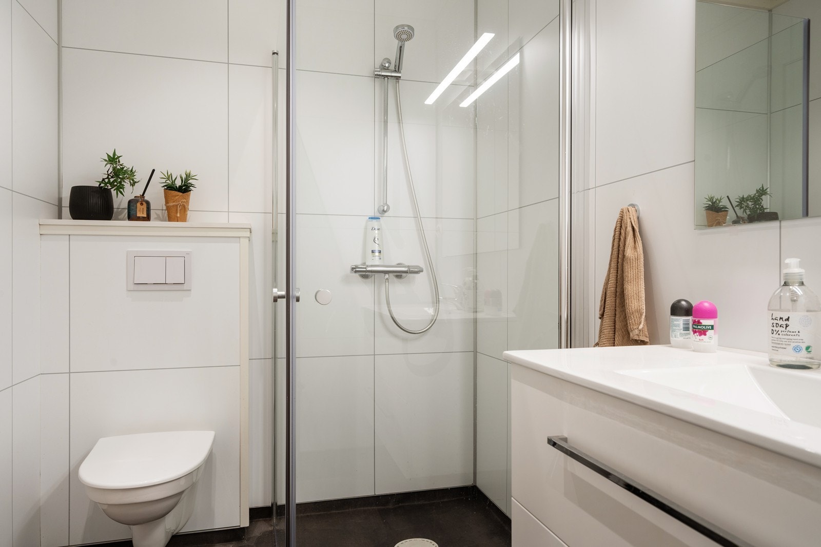 Badet er innredet med vegghengt toalett, dusjnisje og hvit baderomsinnredning med skuffer til oppbevaring Galleribilde