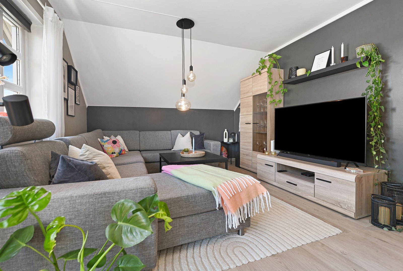 Lyst oppholdsrom med skråtak, store vinduer og moderne belysning. Galleribilde