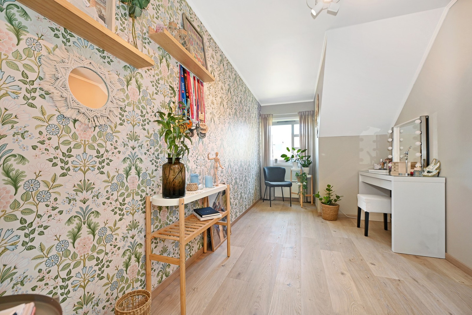 Lyst rom med blomstrete tapet, store vinduer og tregulv. Galleribilde