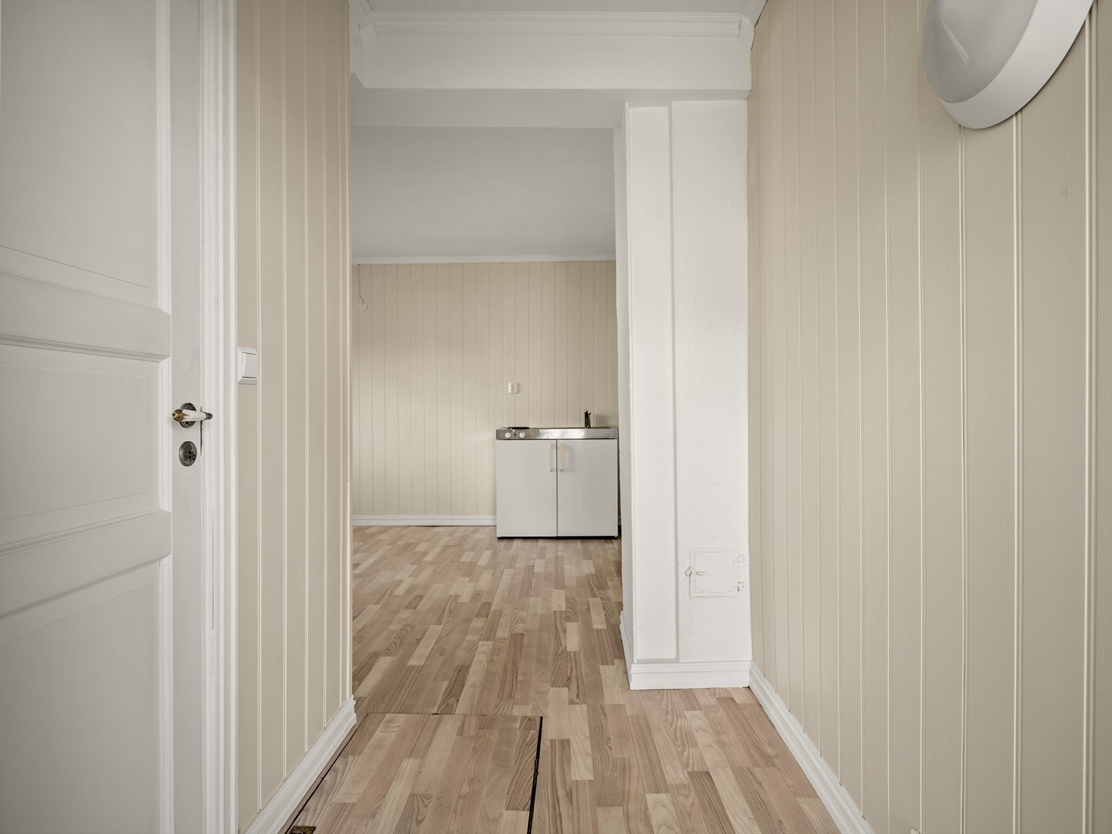 Inngang til den andre delen (hybel) av første etasje, som har laminatgulv og panelvegger. Galleribilde