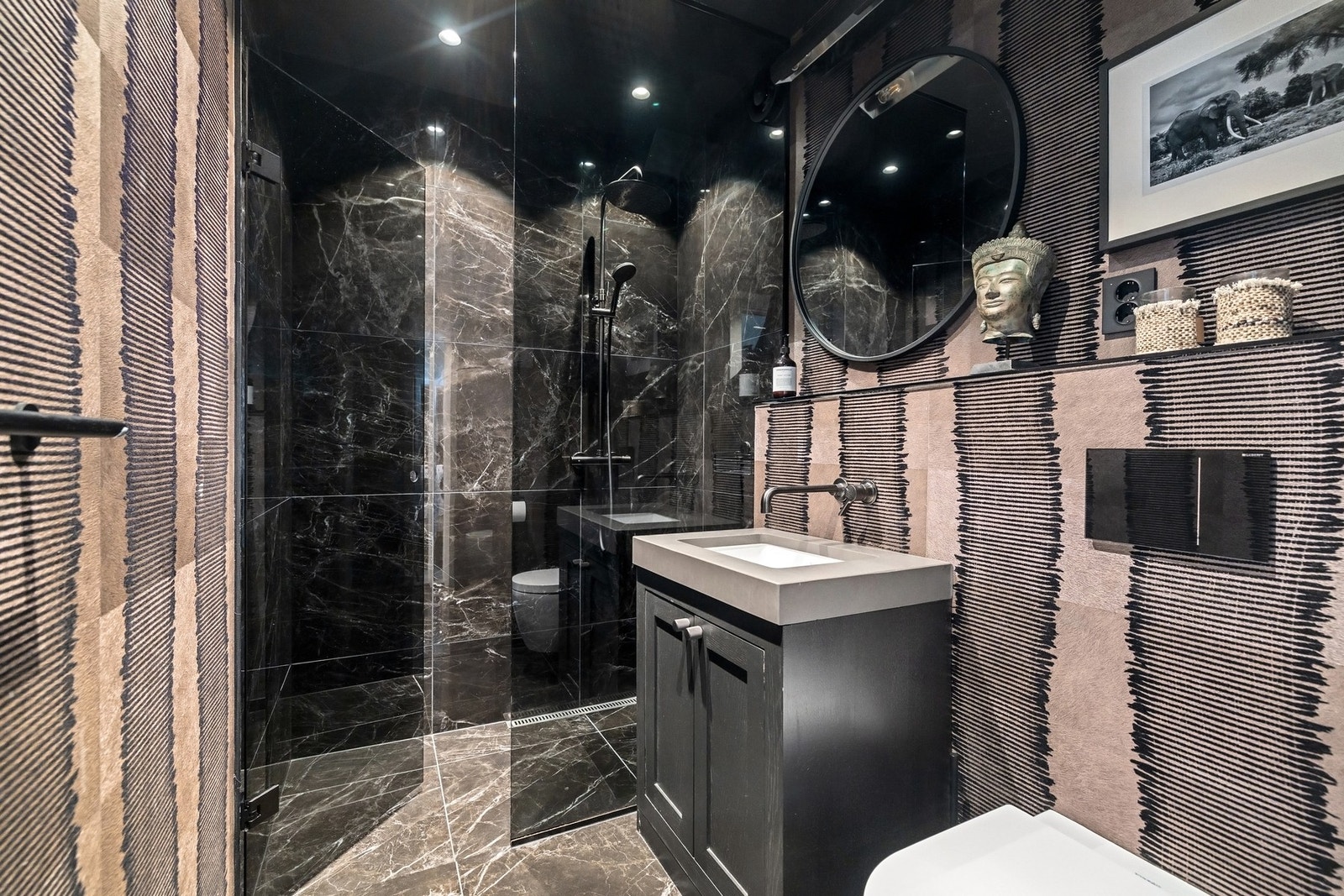 Gjeste bad i hovedetasjen, med dusj armatur i bronse fra italienske Gessi og tapet fra Elitis. Badet har plassbygget skap med sten vask og lampe over speil fra Andrew Martin. Automatisk avtrekksvifte og nye downlights. Galleribilde