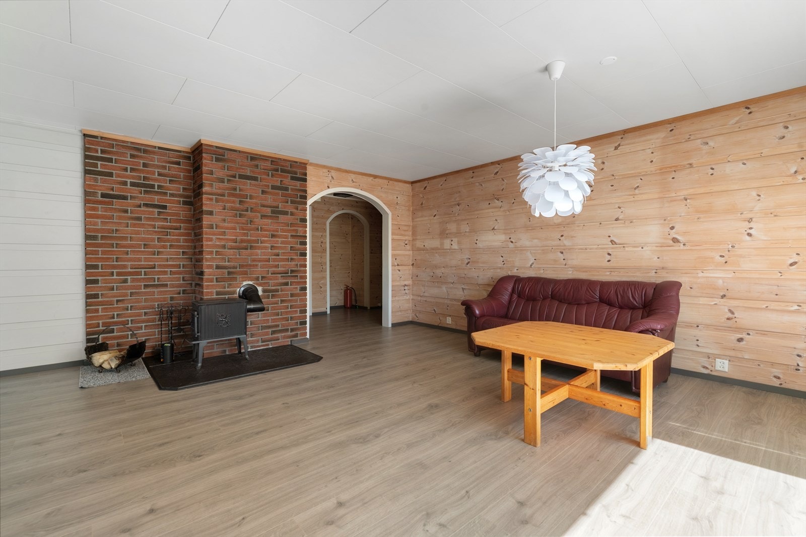 En klassisk vedovn mot en teglsteinsvegg gir stuen en lun atmosfære og en effektiv, alternativ oppvarmingskilde. Galleribilde