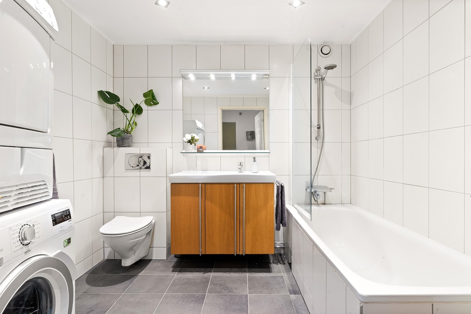 Badet har flislagte overflater, gulvvarme, vegghengt toalett og opplegg for vaskemaskin. Galleribilde