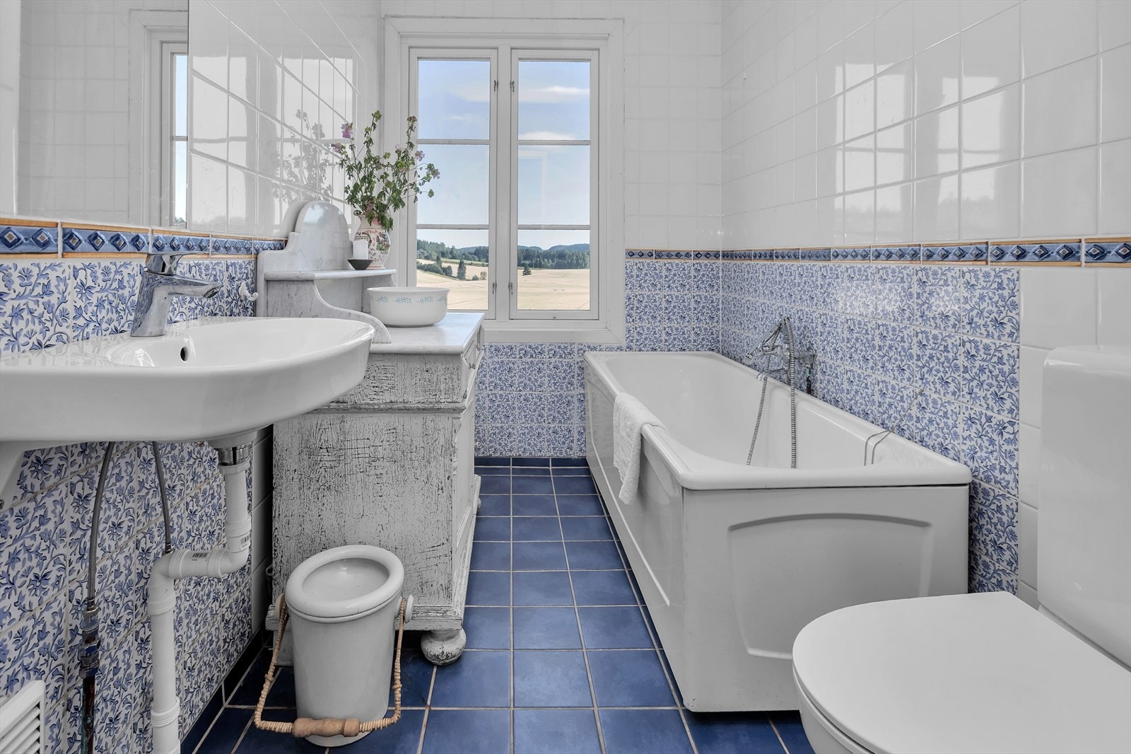 Badet er helfliset, og ble i 2024 oppgradert med ny servant og nytt toalett. Badet har badekar med dusjløsning. Og ikke minst strålende utsikt! I tillegg til et bad på hovedplanet har boligen et vaskerom med dusj i kjelleretasjen. Galleribilde