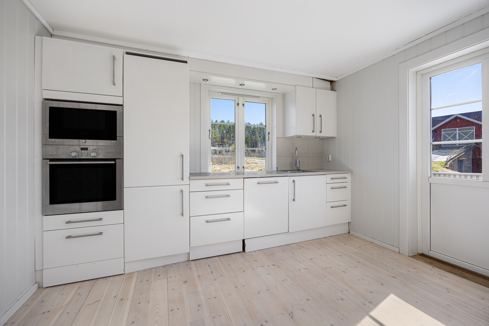 Kjøkkeninnredningen har hvite, glatte fronter, benkeplate av laminat og nedfelt oppvaskkum i stål. I tillegg til platetoppen har kjøkkenet integrert stekeovn, oppvaskmaskin og mikrobølgeovn. Ovnene er praktisk plassert i et høyskap. Galleribilde