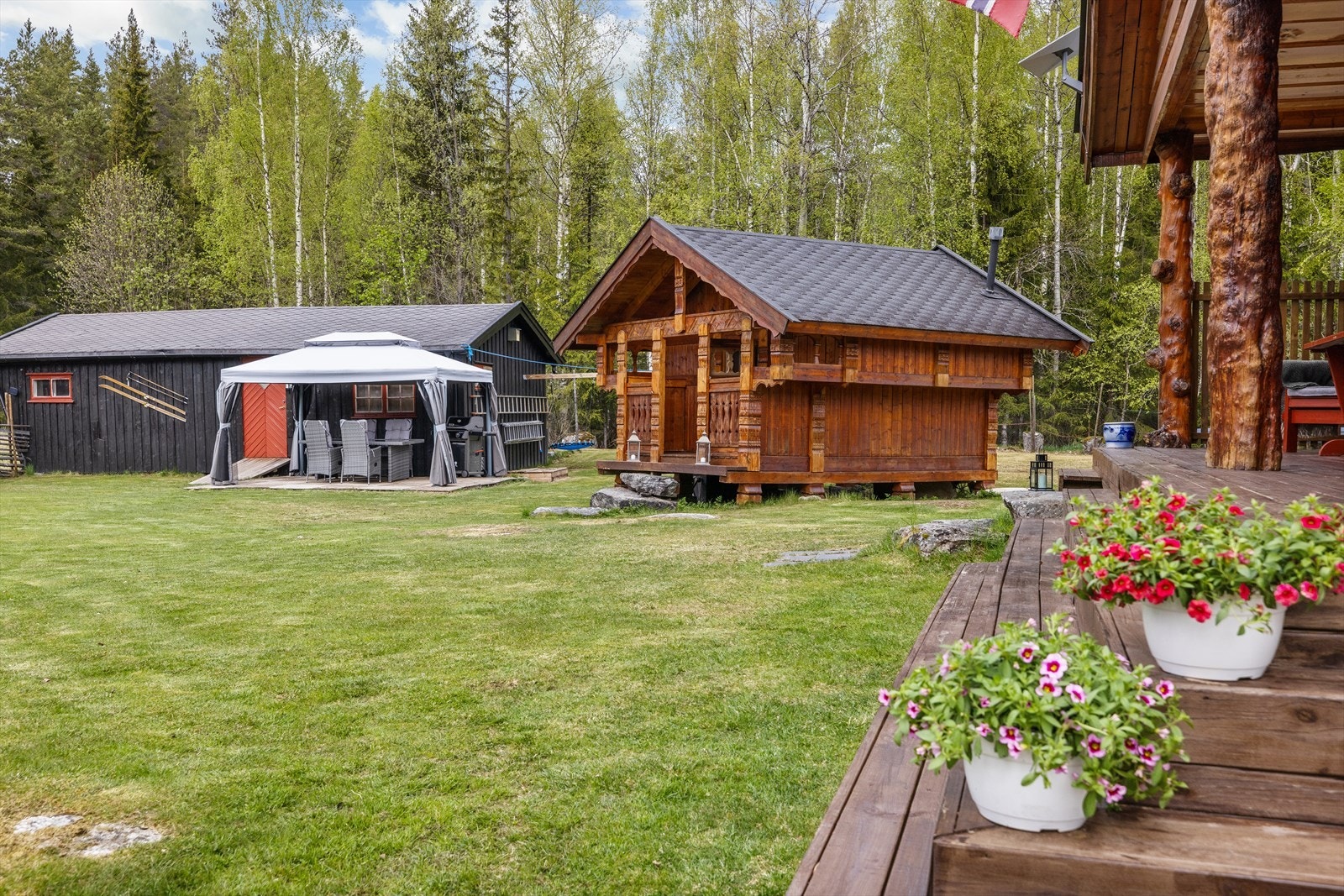Utsikt fra hovedhyttas terrasse mot stabburet og garasjen. Galleribilde
