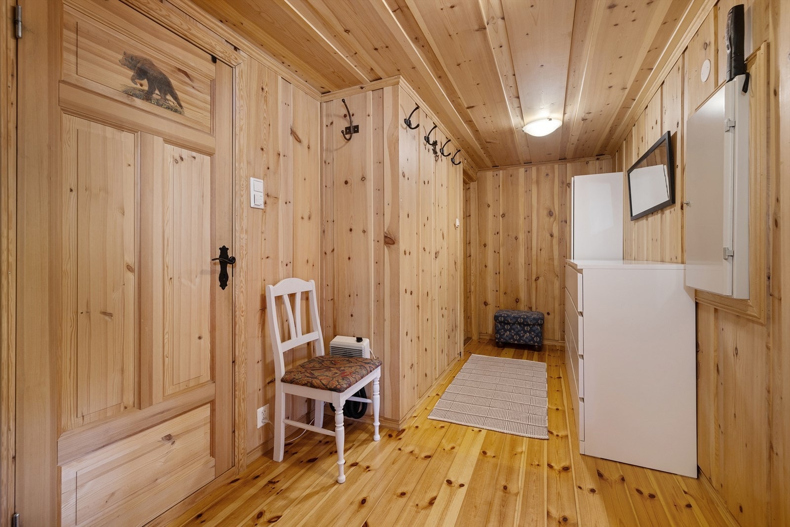 Entré i hytta med god plass til yttertøy og sko. Gjennomgående bruk av heltre på gulv og panel på vegger. Galleribilde