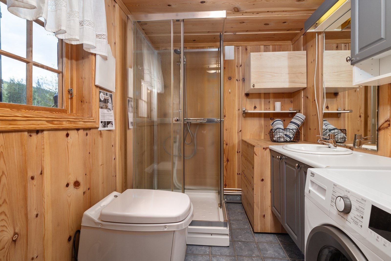 Badet er utstyrt med dusjkabinett, servantinnredning, forbrenningstoalett og opplegg for vaskemaskin. Galleribilde
