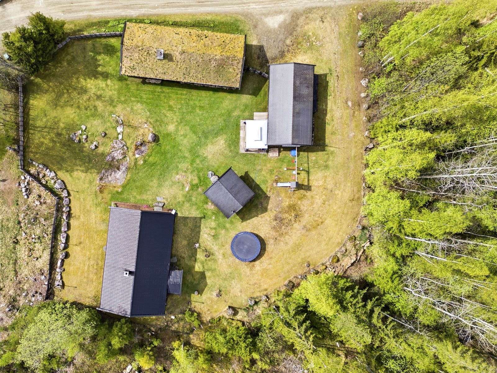 Oversiktsbilde som viser eiendommens fire bygninger og tunet. Galleribilde