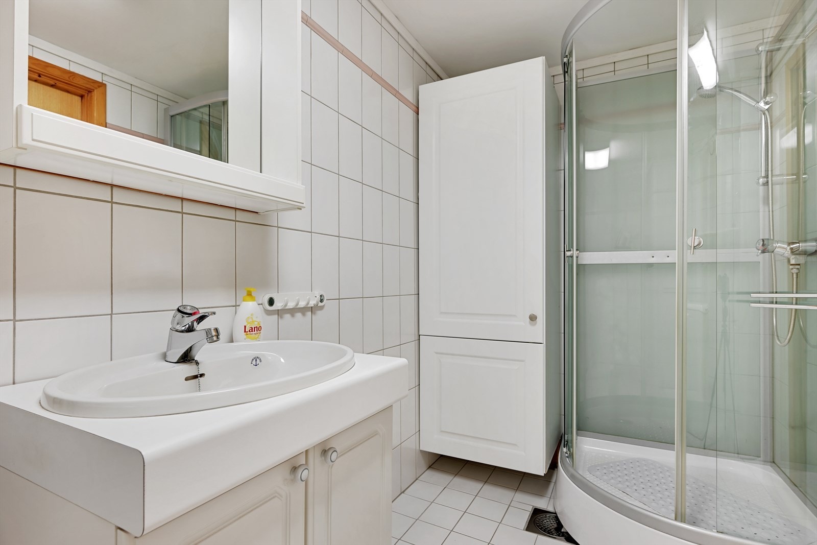Badet er innredet med servantskap og dusjkabinett (vidvinkel gjør at dimensjonen blir forstørret). Galleribilde
