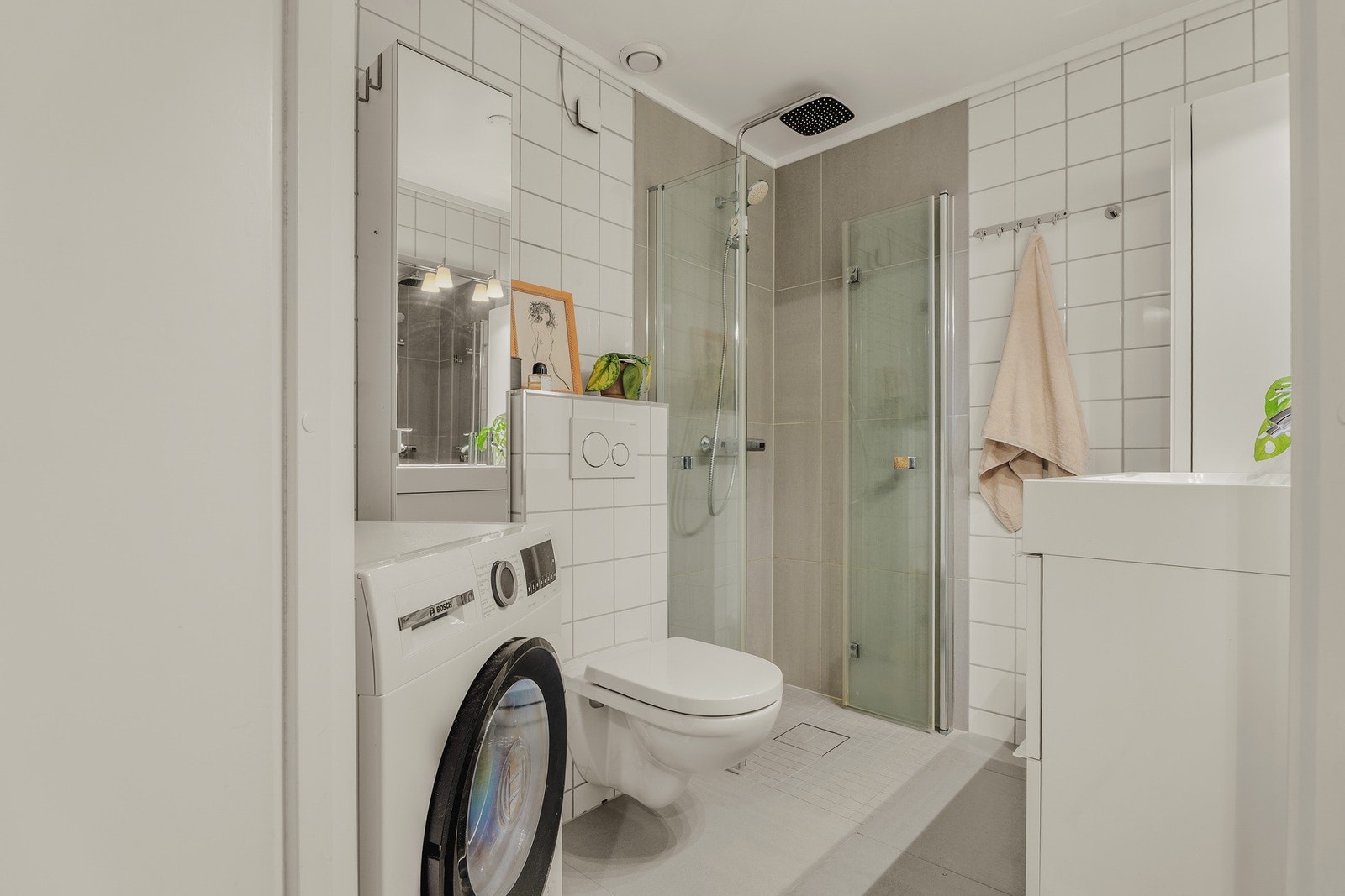 Fra entreen finner vi inngangen til badet. Det ble oppgradert av fagfolk i 2018, med blant annet gulvvarme, vegghengt toalett, foldbare dusjvegger i glass, samt fliser på gulv og i dusjsonen. Galleribilde
