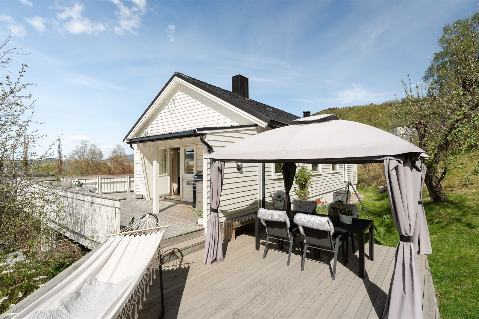 Fra hovedetasjen er det utgang til et stort terrasseområde som strekker seg rundt deler av boligen. Galleribilde