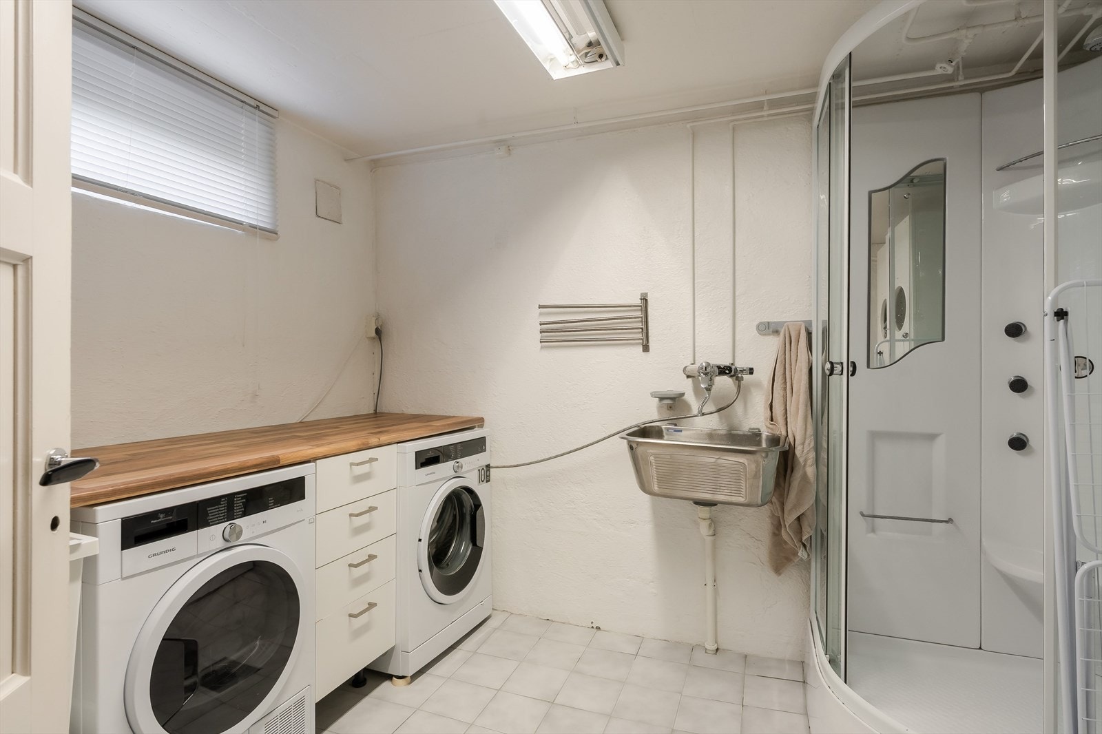 I sokkeletasjen ligger vaskerom/dusj med opplegg for vaskemaskin, tørketrommel, skyllekum og dusjkabinett. Rommet har en praktisk bruksfunksjon i hverdagen, med benkeplate over hvitevarene og god arbeidsflate til klesvask. Galleribilde