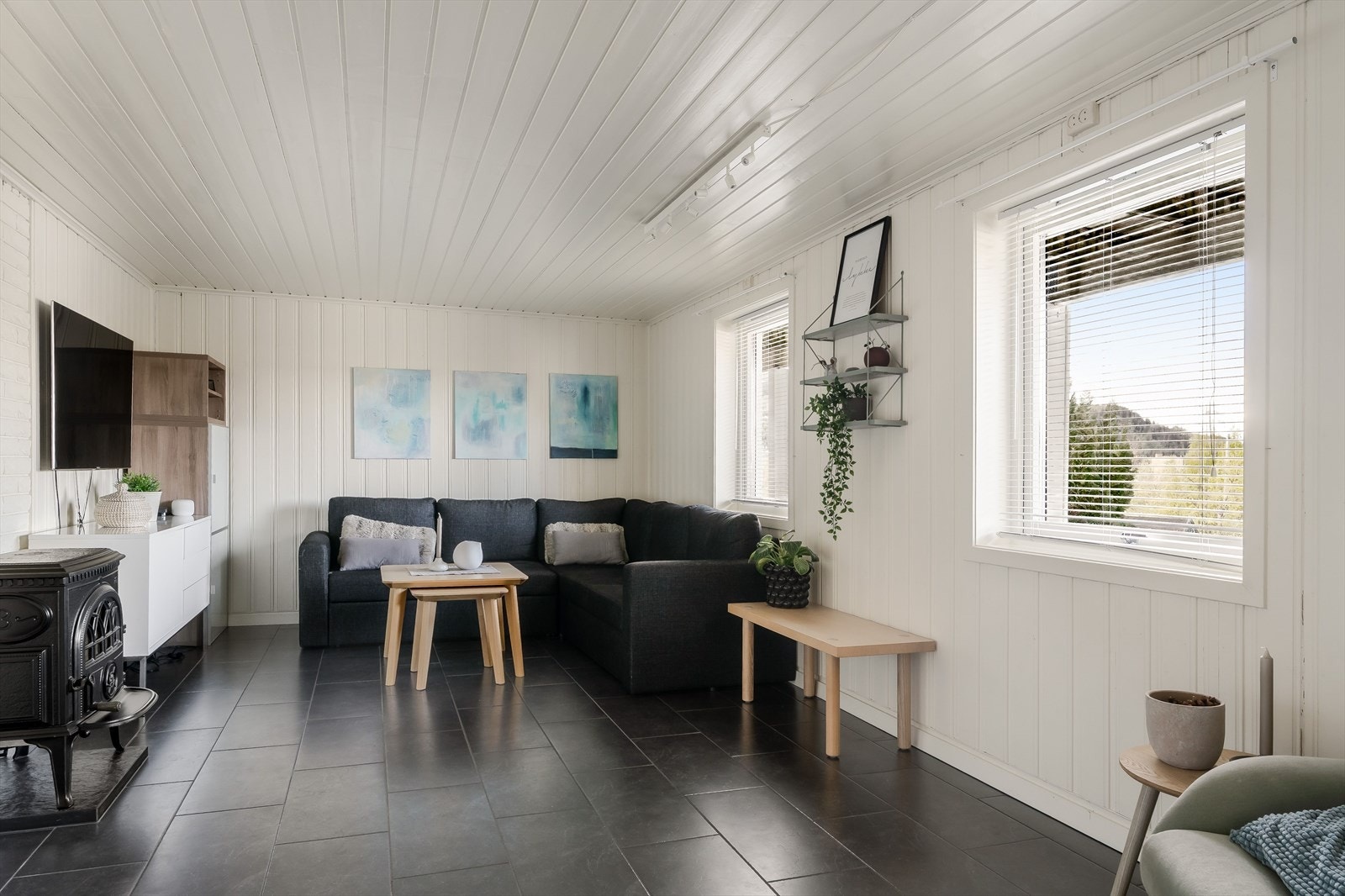 Et av rommene er innredet som en hyggelig kjellerstue, med lyse panelvegger, mørke gulvfliser, flere vinduer og god plass til sofagruppe. Galleribilde