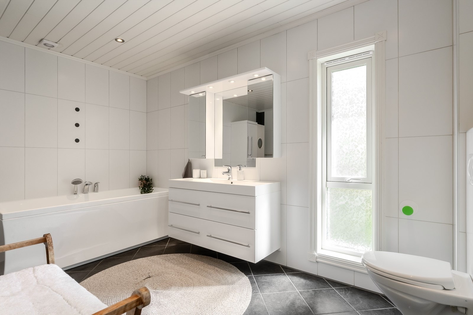 Badet i hovedetasjen er romslig og har en lys utførelse med flislagte vegger, mørke gulvfliser og hvit himling. Badet ble utvidet og oppgradert i 2010. Galleribilde