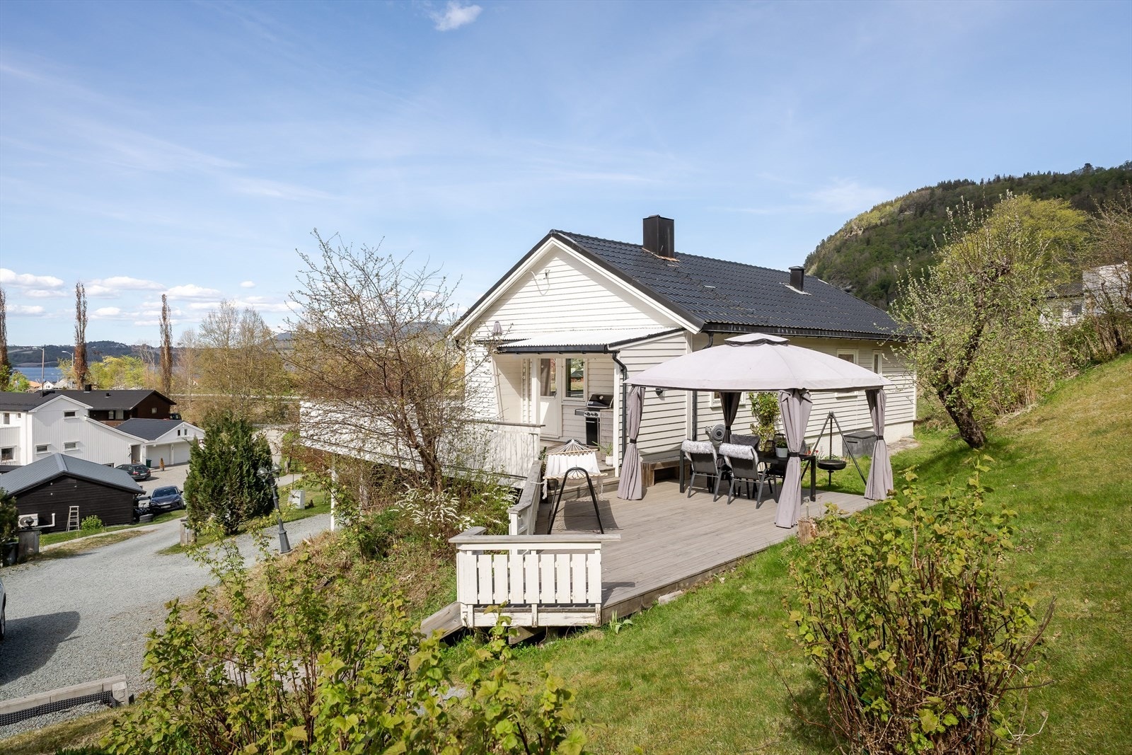 Rundt boligen er det grønne omgivelser, hageareal og en åpen beliggenhet som gir en luftig og landlig ramme rundt eiendommen. Galleribilde