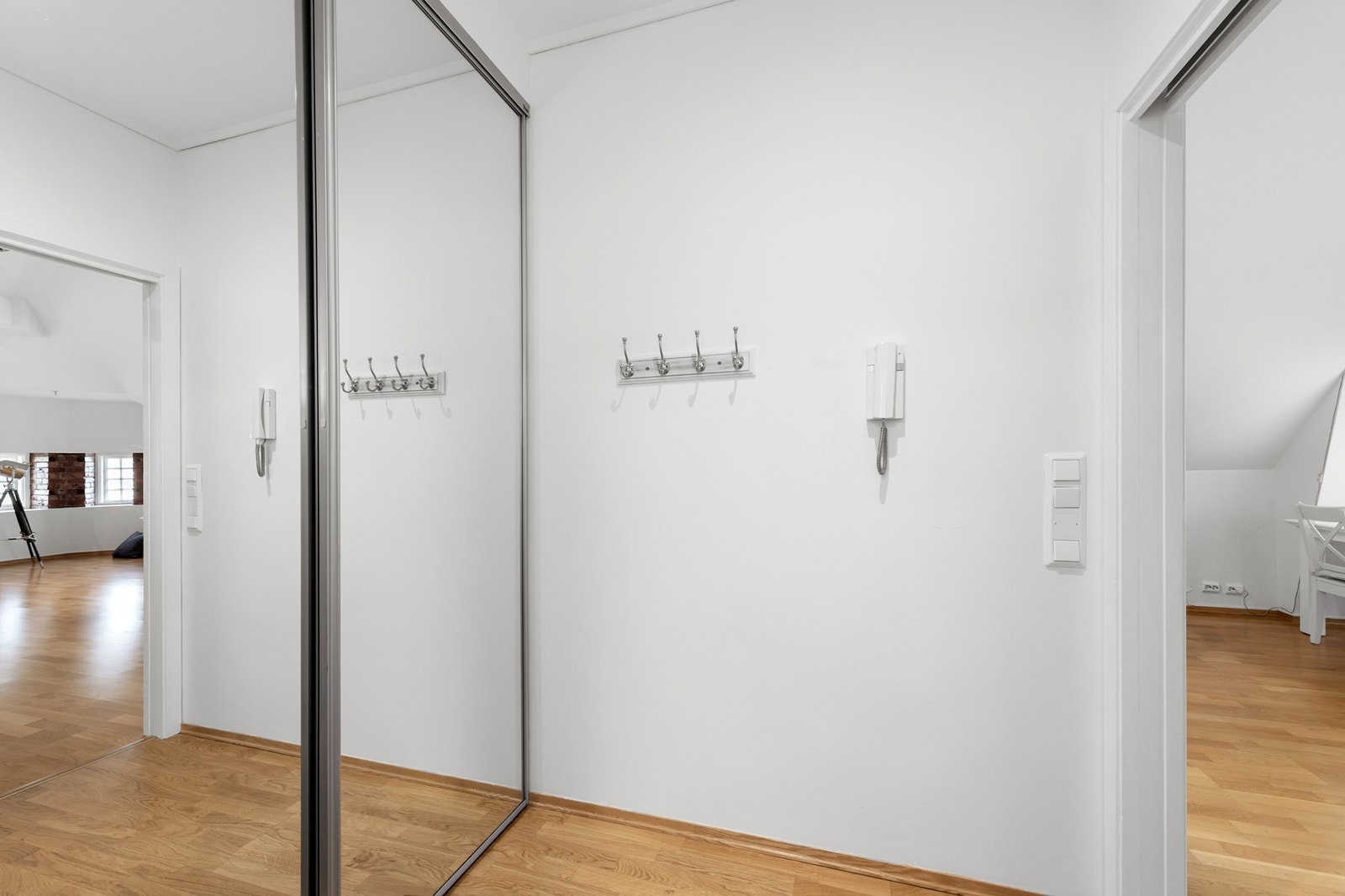 Lys og innbydende gang med stor skyvedørsgarderobe med speildører og porttelefon. Galleribilde