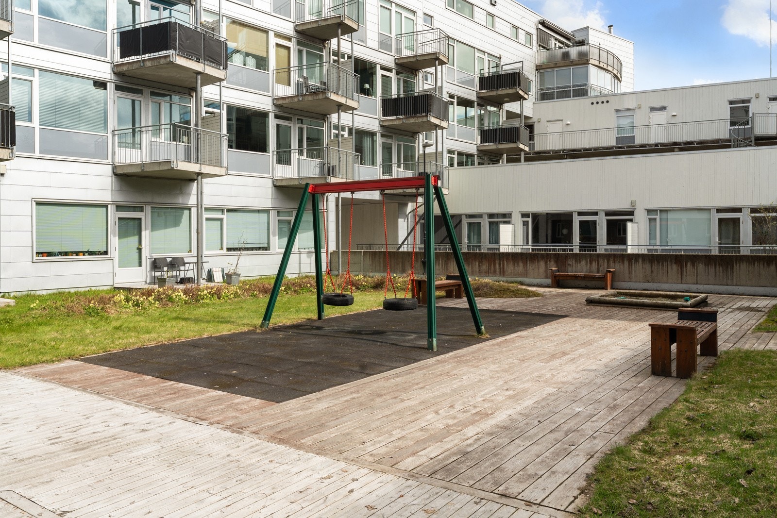 Pent opparbeidet uteområde med grøntarealer, sittebenker og lekeplass for de minste barna. Galleribilde