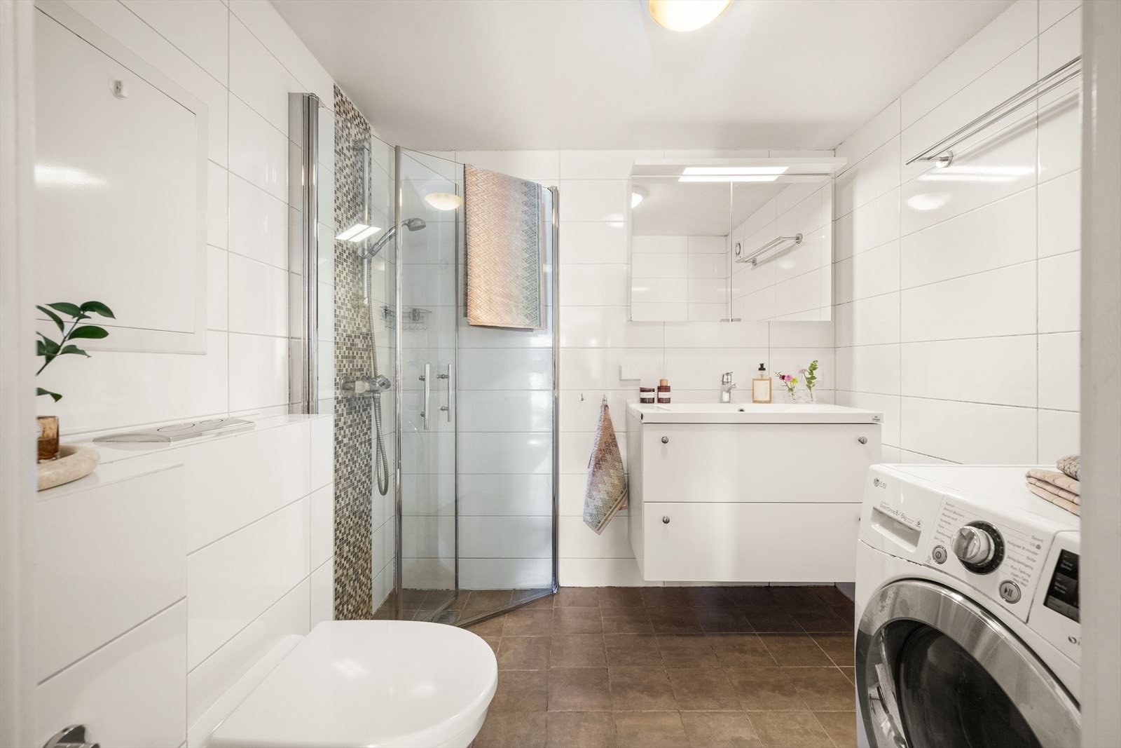 Stort bad fra 2013 med elektrisk gulvvarme. Innredet med vegghengt klosett, servant nedfelt i innredning og speilskap med lys. Dusjhjørne med svingbare glassdører. Opplegg for vaskemaskin og elektrisk styrt vifte. Galleribilde