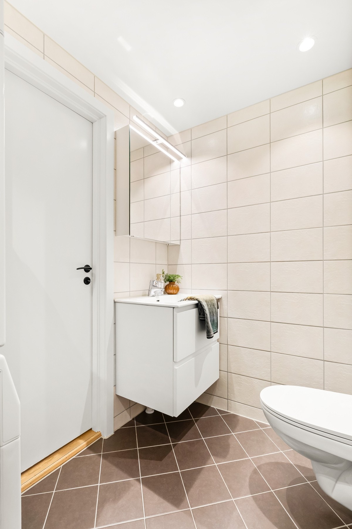 Badet har en lys og moderne utførelse med spotter i taket, speilbelysning og behagelige varmekabler i gulvet Galleribilde