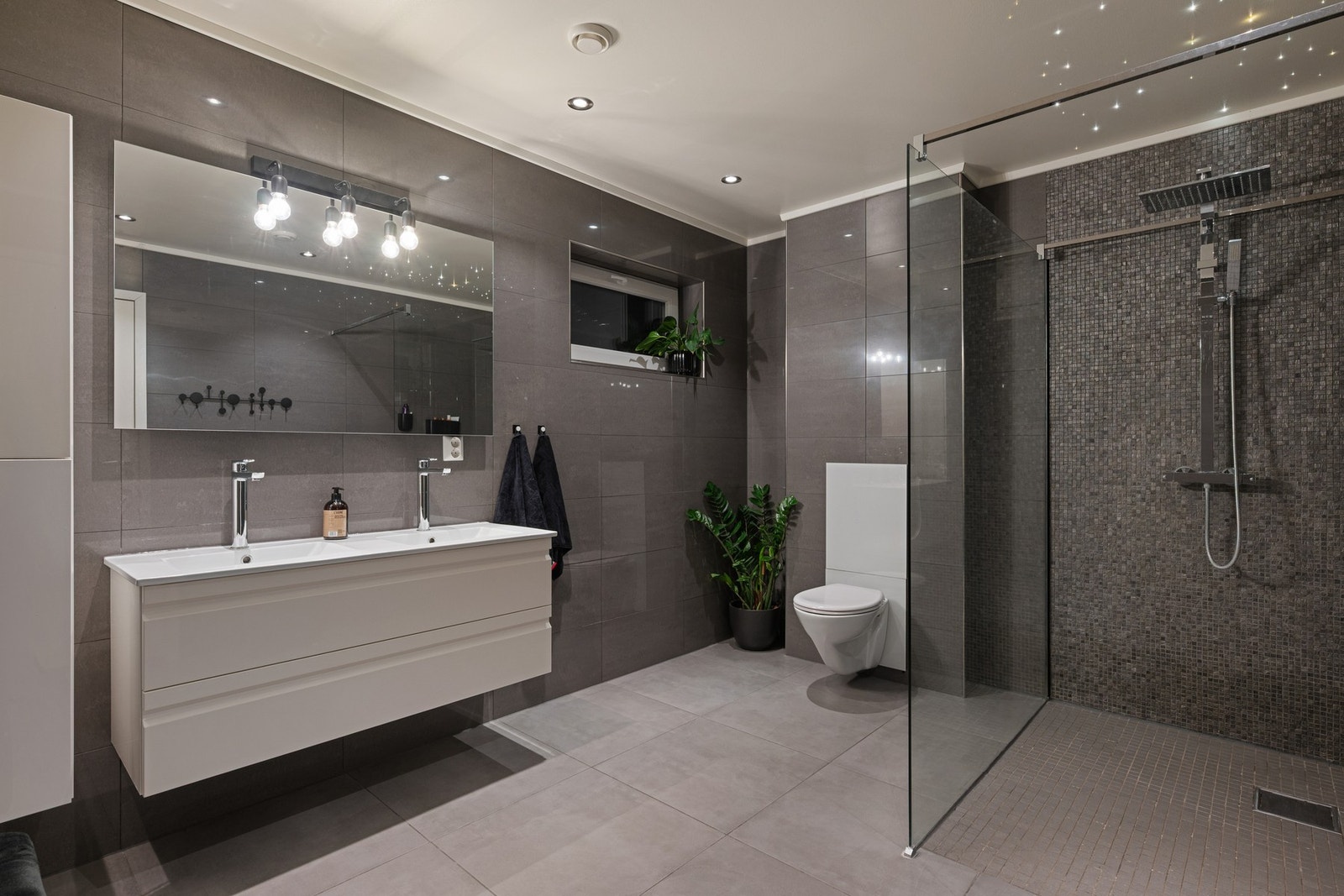 Badet i 1. etasje holder samme gjennomgående, moderne standard med flislagte overflater og vannbåren varme i gulvet. Galleribilde