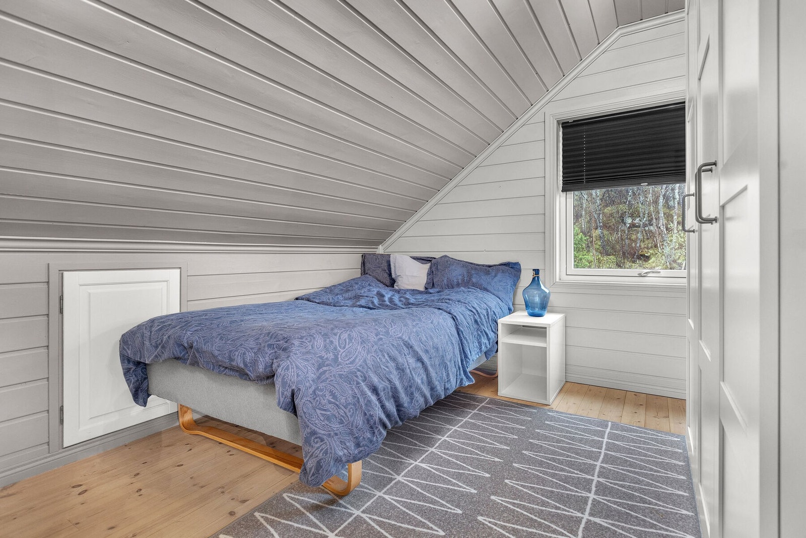 Soverom på loftet med malt trepanel på vegger og i tak. Galleribilde