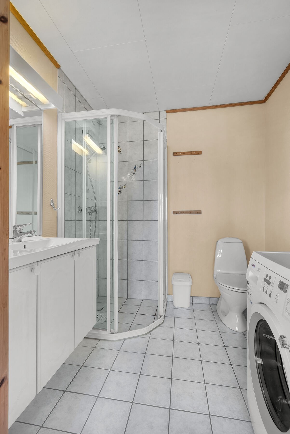 Badet i utleiedelen har flislagt gulv med vannbåren varme, dusjhjørne og opplegg for vaskemaskin. Galleribilde