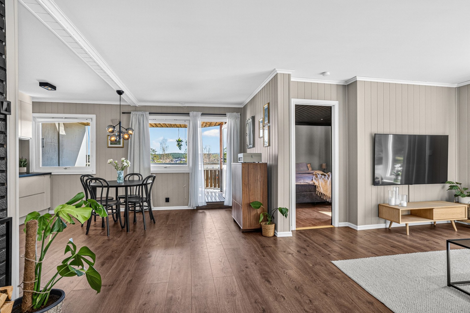 Lys og innbydende stue med 1-stavs laminatgulv, panel på vegger og slett flate i himling Galleribilde