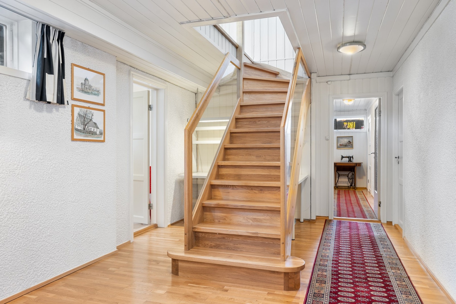 Fra hallen går veien ned til kjelleretasjen i hoveddelen via en moderne trapp med glassvegger. Her finner du en romslig kjellerstue, praktisk vaskerom, bad nr. 2, badstue og rikelig med lagringsplass i boder. Galleribilde