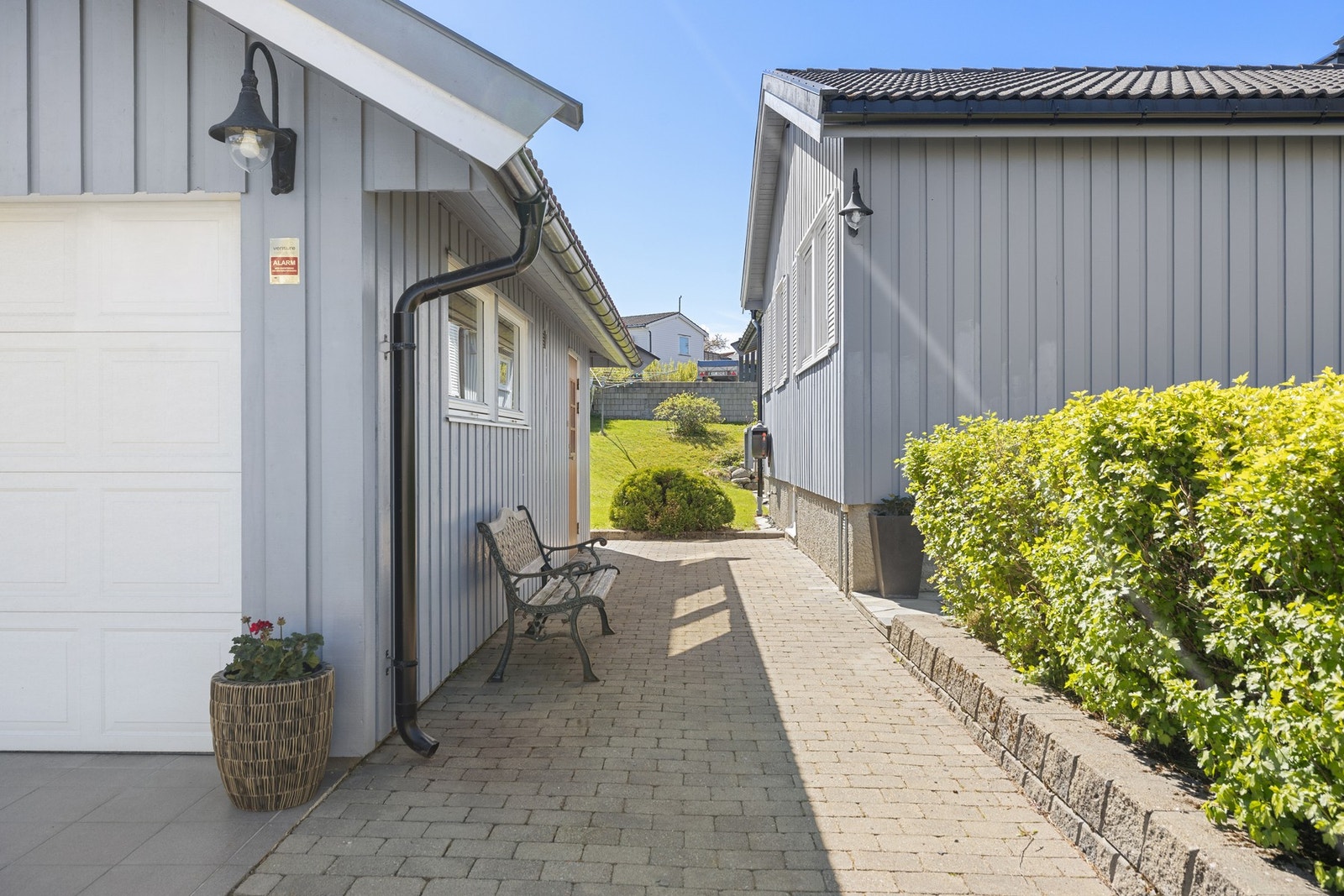 Langs boligen er det etablert praktiske og velstelte gangarealer med belegningsstein og grønne hekker som skaper en lun og ryddig adkomst. Galleribilde