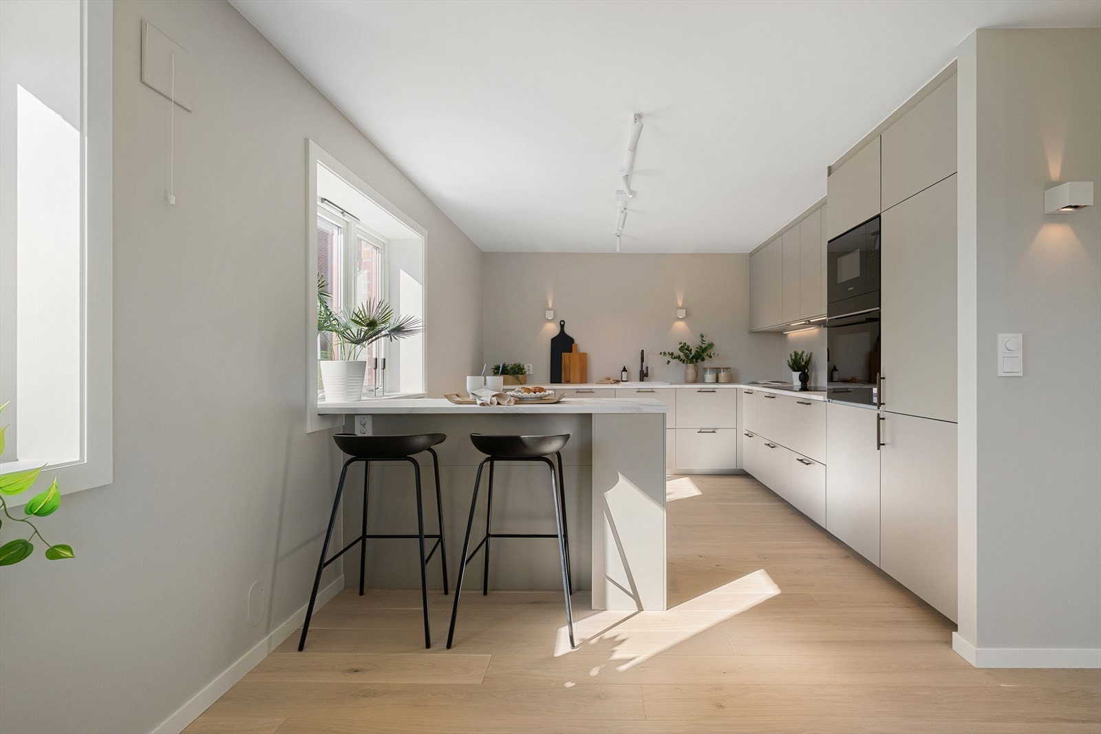 Stilrent kjøkken med marmormønstret benkeplate og detaljer i bronsefarge. Galleribilde