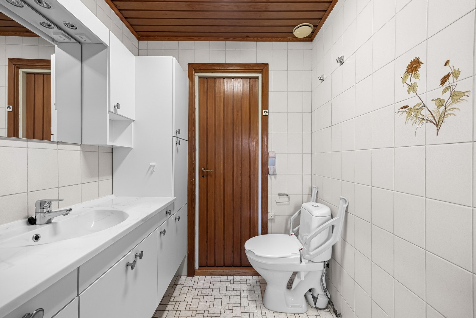 Badet er innredet med fliser, toalett og åpent dusjhjørne Galleribilde