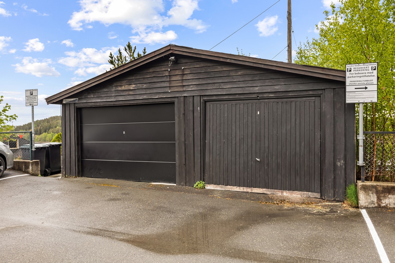 Dobbelgarasje med to separate rom på henholdsvis ca. 18 og 26 kvm. Begge er utstyrt med fjernstyrte porter, og foran garasjen er det en asfaltert biloppstillingsplass. Galleribilde