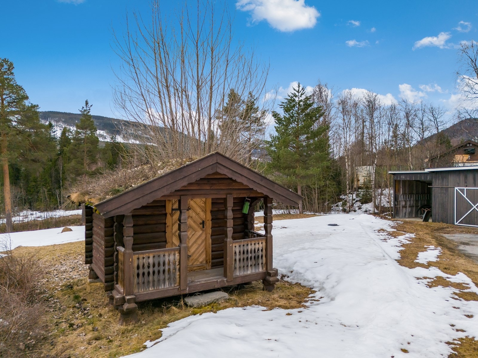 Det laftede stabburet fra 1981 er en sjarmerende detalj på eiendommen, komplett med torvtak og en liten sval. Galleribilde