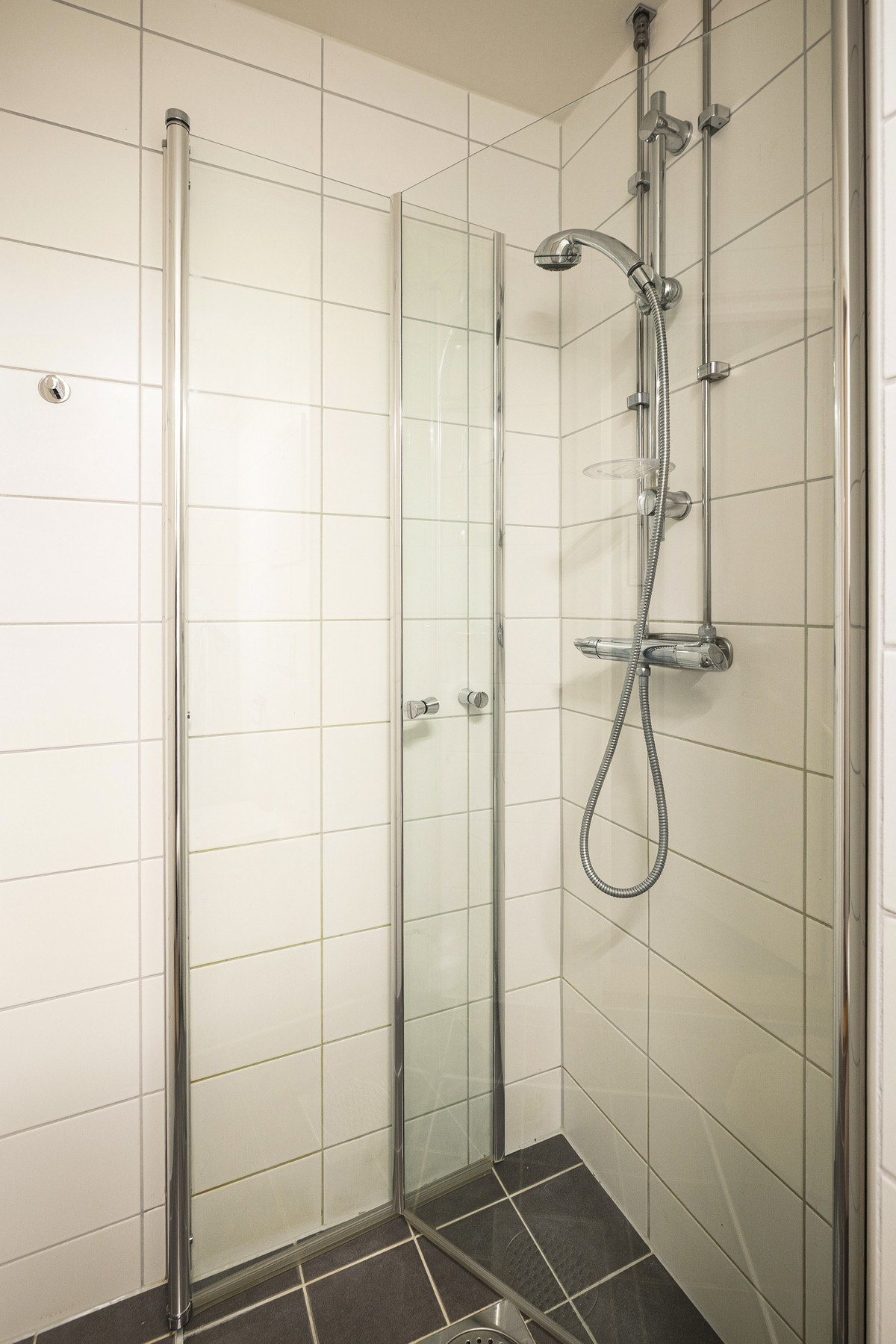 Badet er innredet med vegghengt servantinnredning, speilskap med belysning, dusjhjørne med glassdører og vegghengt toalett. Galleribilde