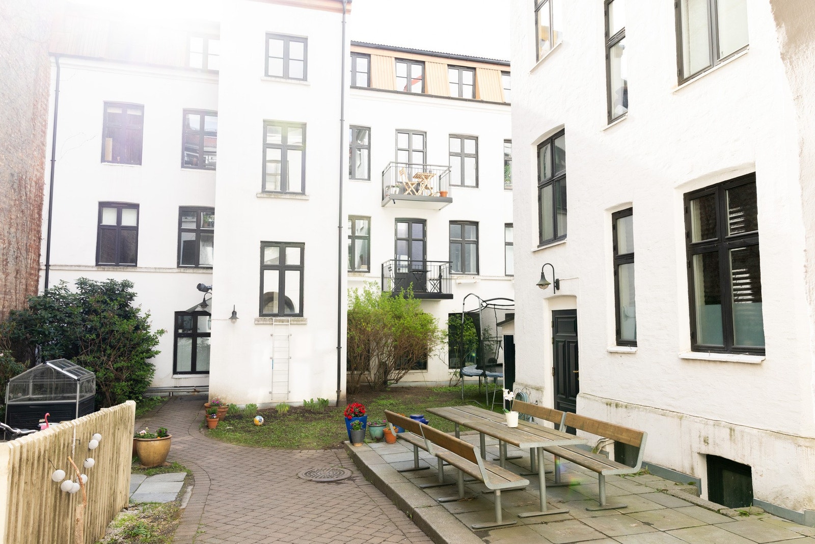 Pent opparbeidet og skjermet bakgård med sittegrupper trampoline og beplantning. Galleribilde