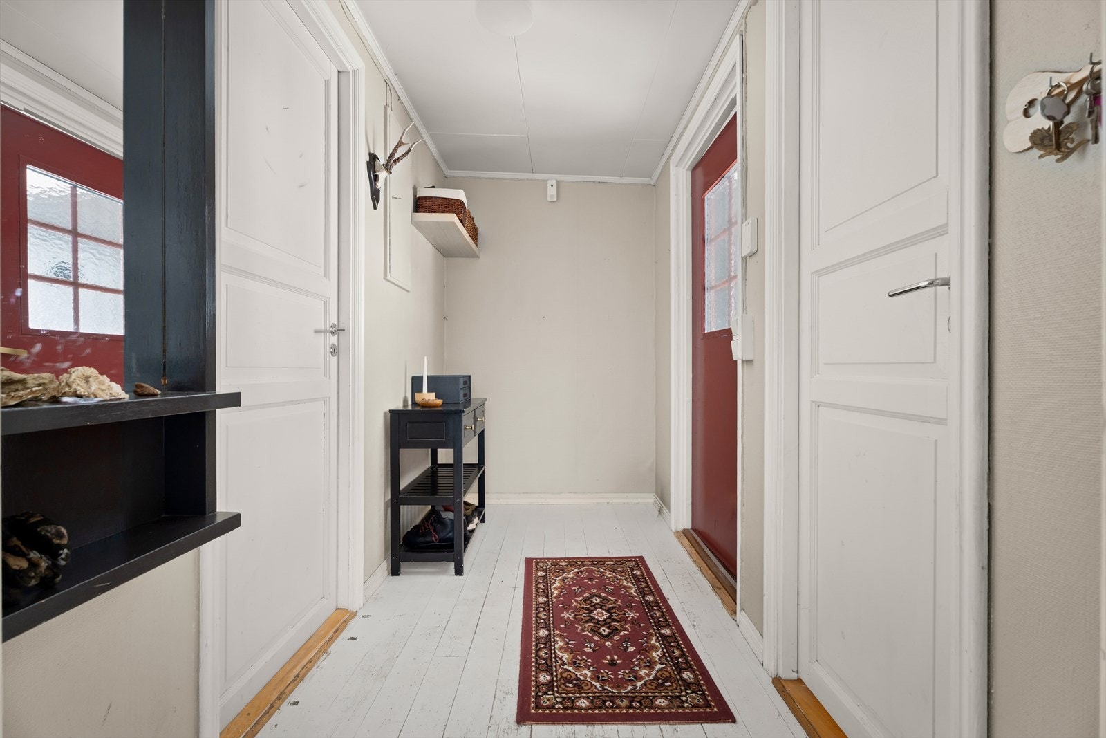 Entréen ønsker velkommen med malte tregulv og gir tilgang til boligens praktiske vaskerom og toalettrom. Galleribilde