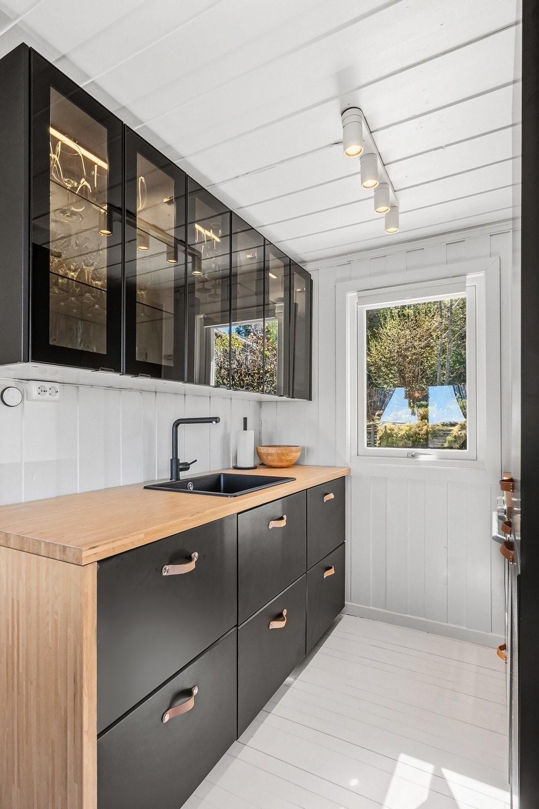 Kjøkkenet fra 2020 har svarte, glatte fronter og sotede glassfronter kombinert med 38mm tykk benkeplate i elegant bambusfinér. Galleribilde
