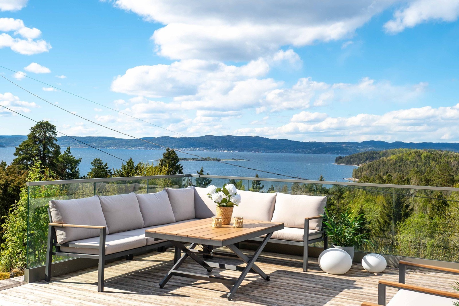 Stilig glassrekkverk forsterker følelsen av nærhet til fjorden og kontakt med grønne omgivelser. Galleribilde